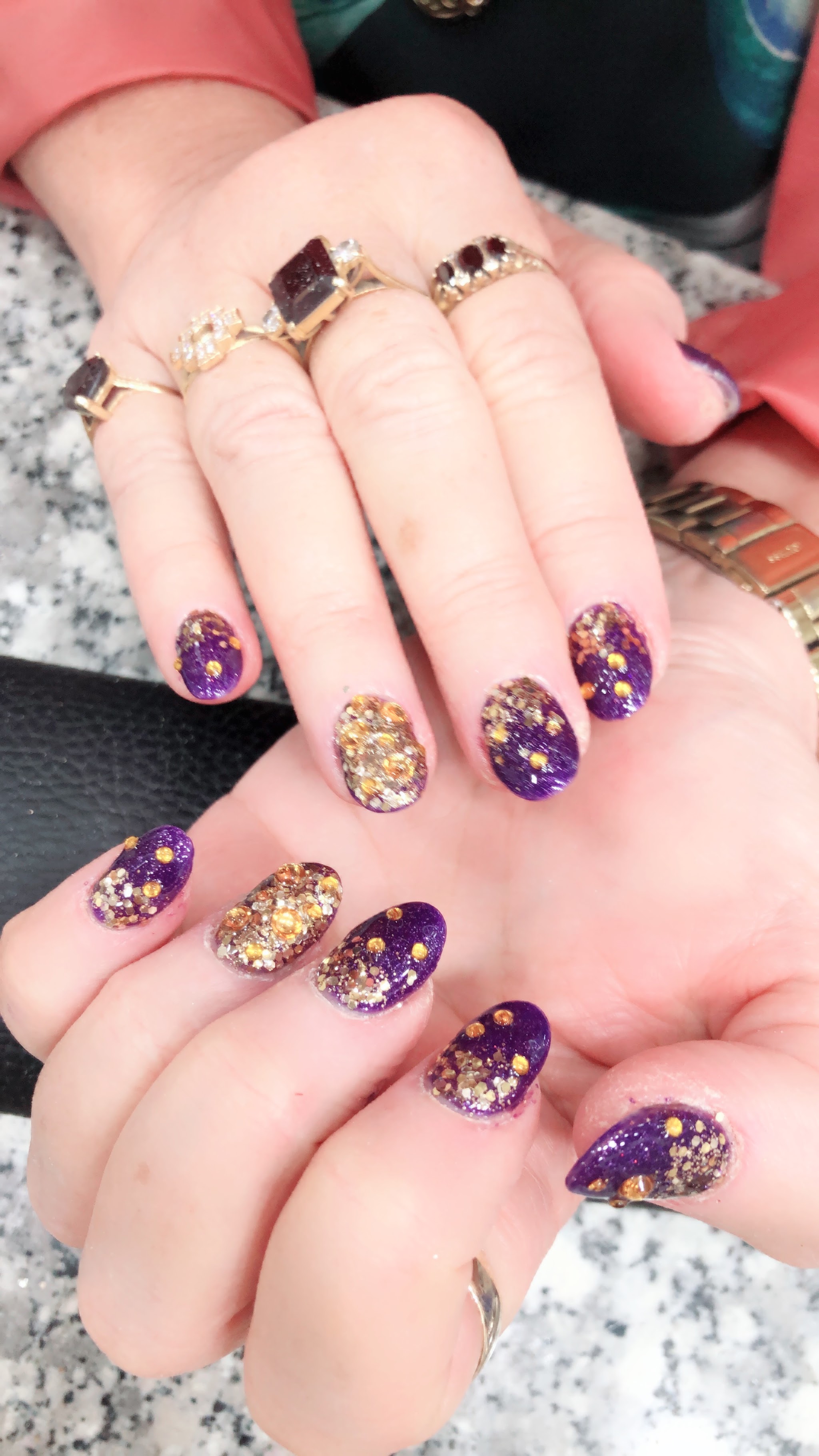 Purple and gold glitter gel nails with rhinestone accents
