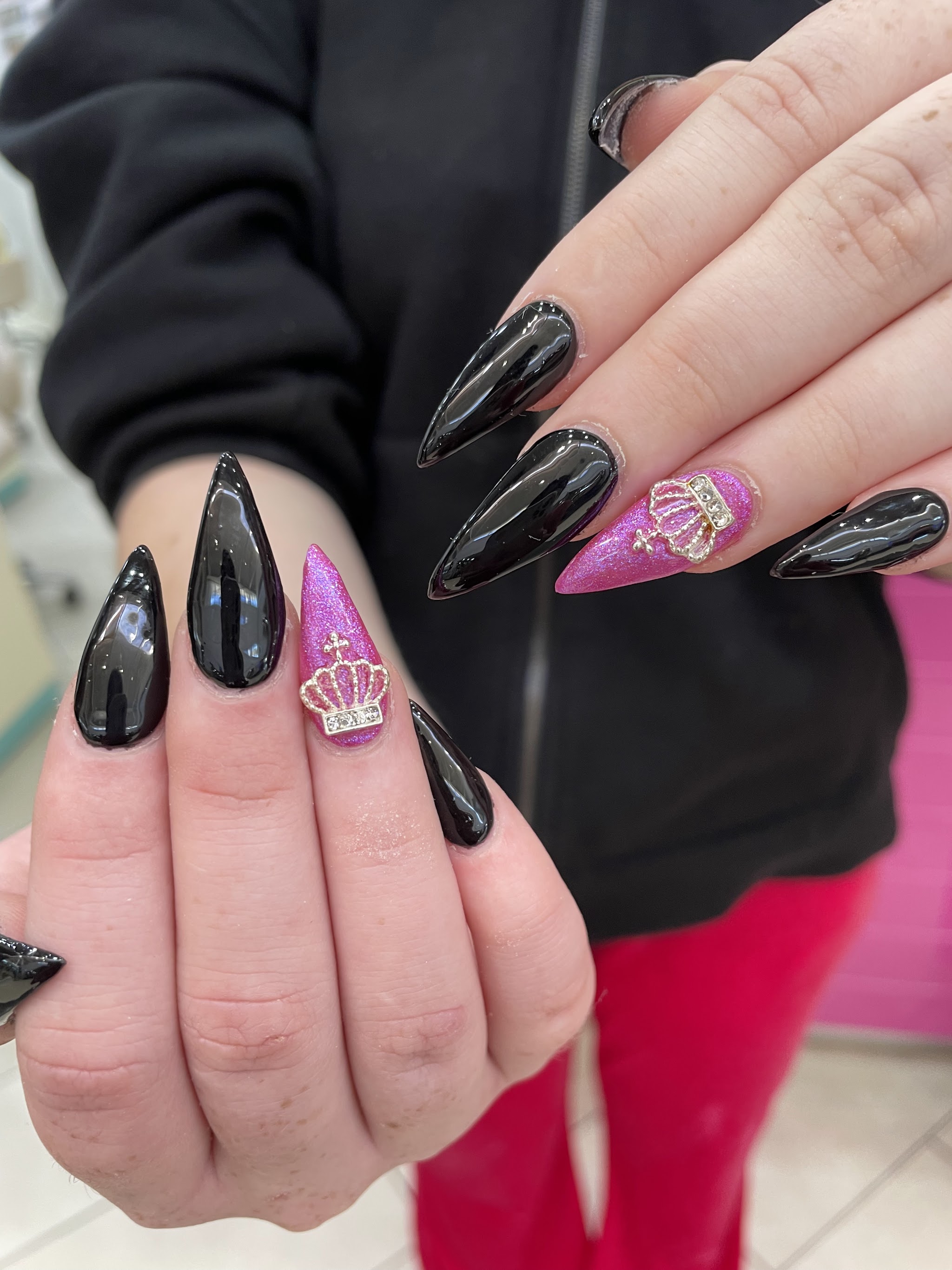 Black stiletto nails with a pink crown charm on the accent nail